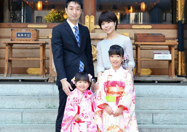 境内の前に立つ娘二人と両親の家族写真
