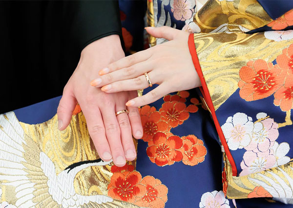 色打掛を纏った新婦と紋付袴の新郎が、結婚指輪をはめた手を重ね合わせる手元のクローズアップ