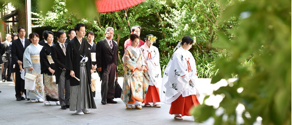 巫女の後を歩いて行く新郎新婦とその家族